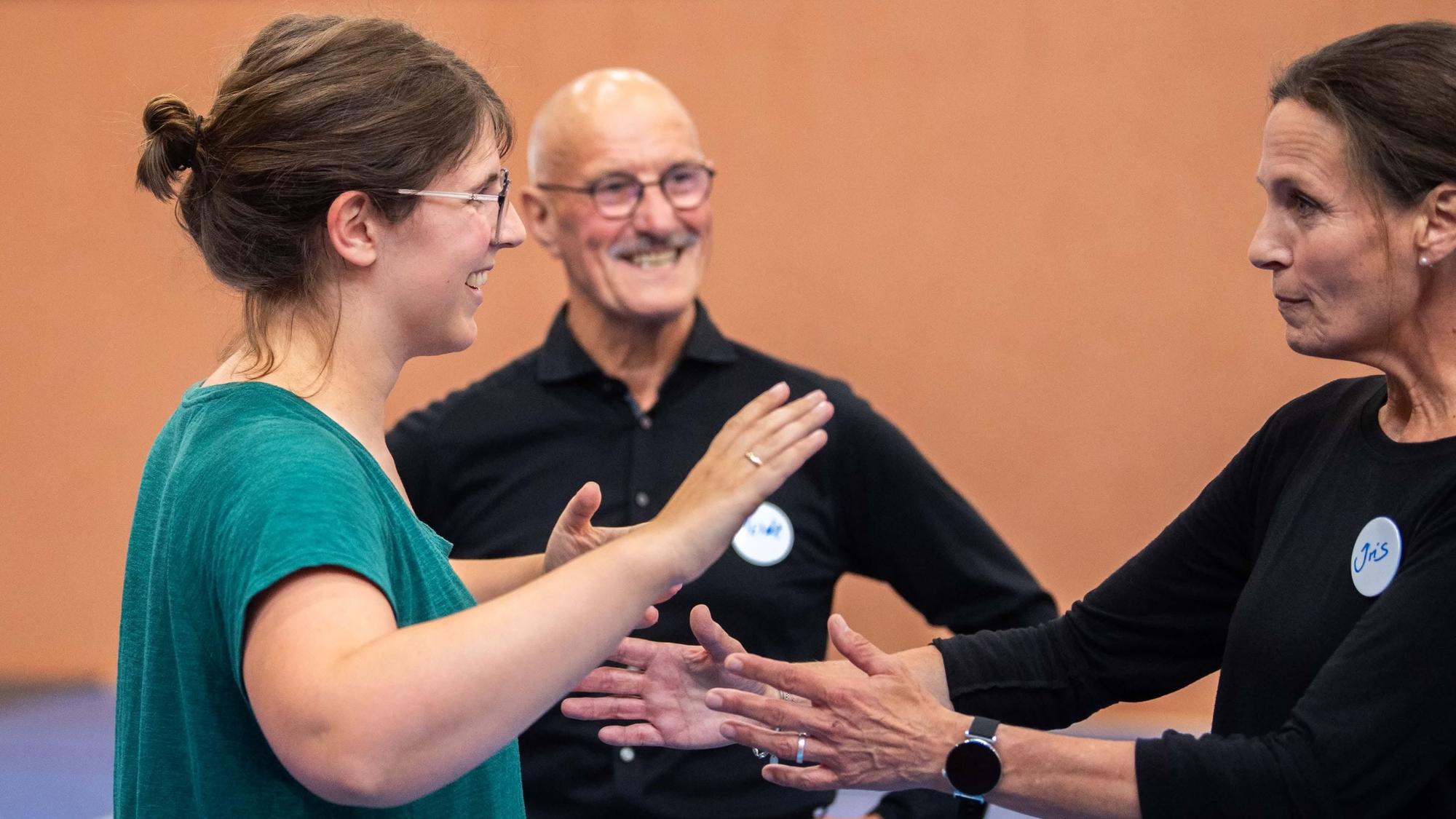 Das Bild zeigt Tanzlehrerin Iris und Tanzexperte Heinrich Schmitz, wie sie Redakteurin Julia Reuß die richtige Haltung erklären.
