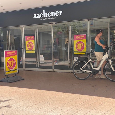 Zu sehen ist der Eingang des Modehauses Aachener in Brühl.