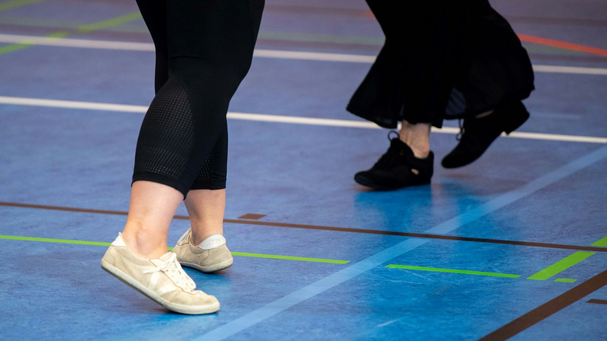 Das Bild zeigt vier Füße, die über den Boden gleiten.