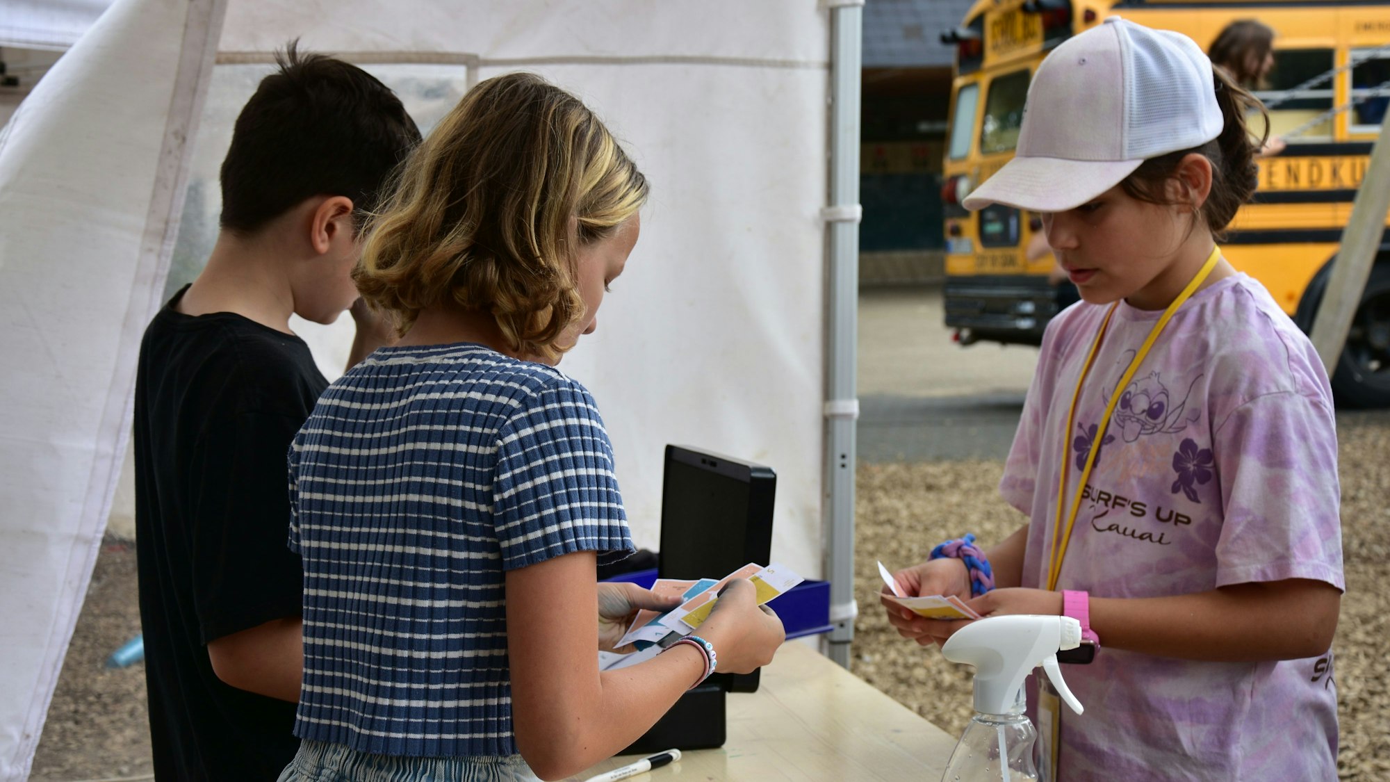 Kinder in einem Pavillonzelt, es wird Spielgeld ausgezahlt.