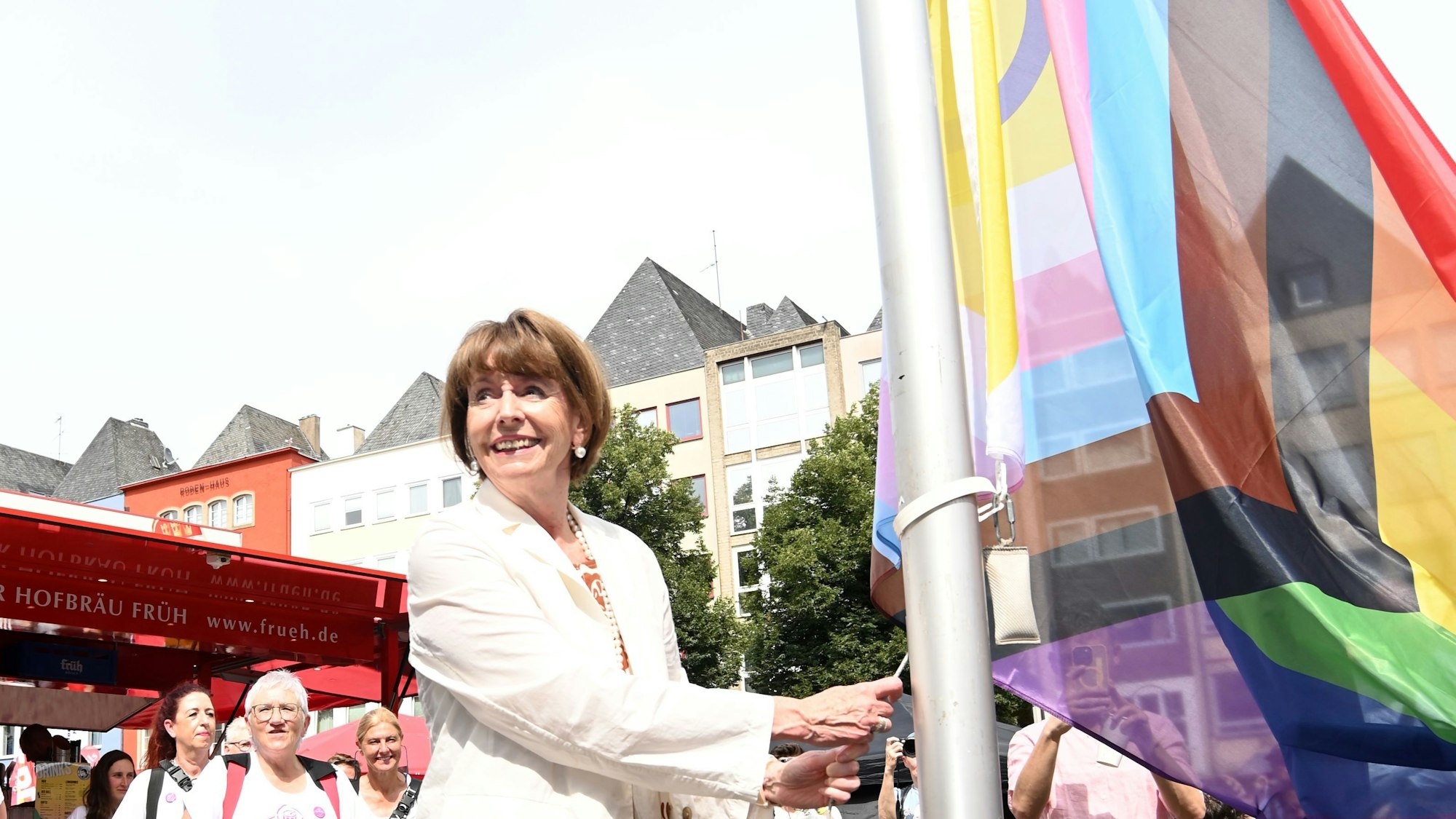 Oberbürgermeisterin Reker hisst lächelnd am Rathaus auf der Alter Markt die Progress-Pride-Flagge