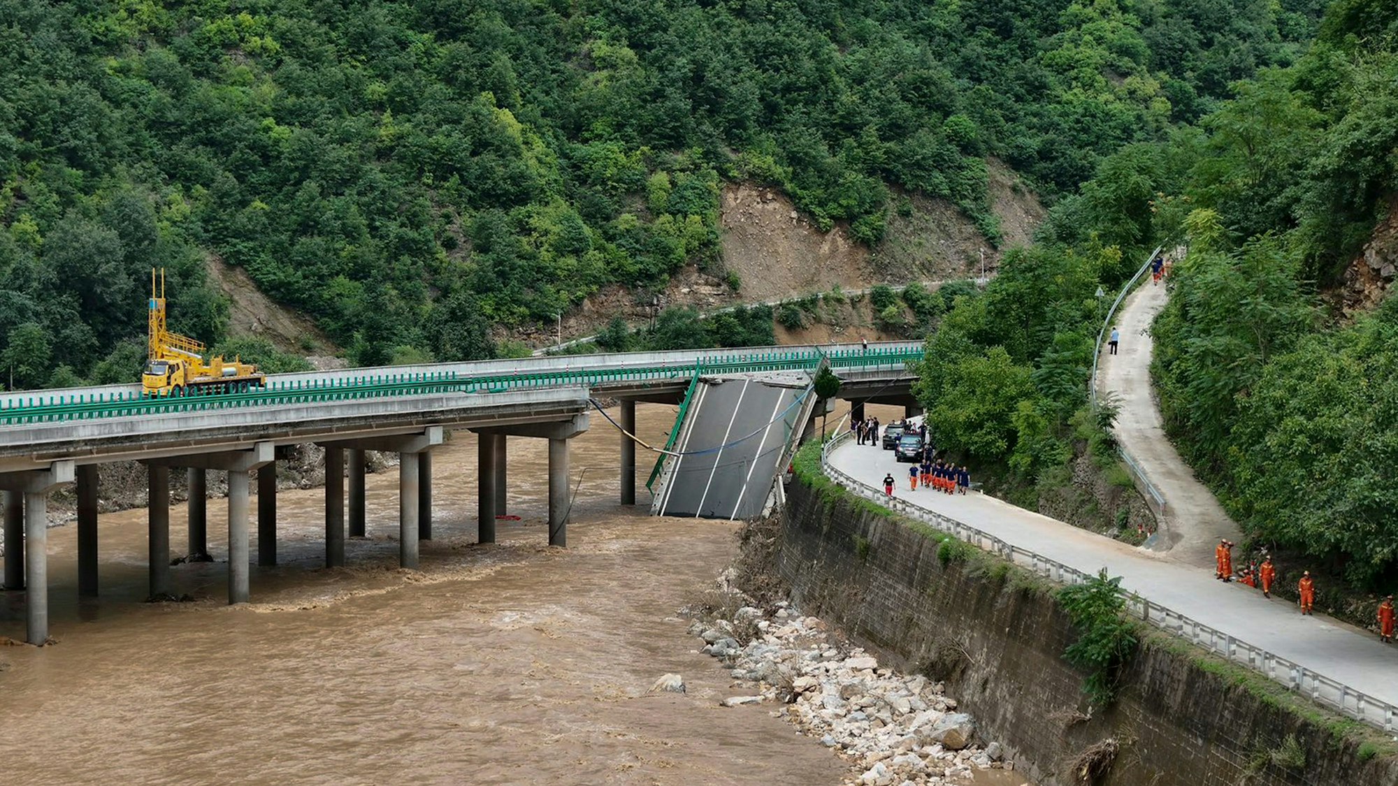 In this photo released by Xinhua News Agency, rescuers work near a collapsed bridge in Zhashui County in Shangluo City, northwest China's Shaanxi Province, Saturday, July 20, 2024. Chinese authorities say several people have died and more than dozen are missing in the partial collapse of a highway bridge in the northwest of the country following heavy storms and flooding. A similar number are missing in the southwest after dozens of houses were destroyed by storms. (Zhao Yingbo/Xinhua via AP)