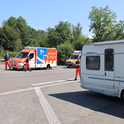 Mehrere Rettungssanitäter stehen an einem Wohnwagen.