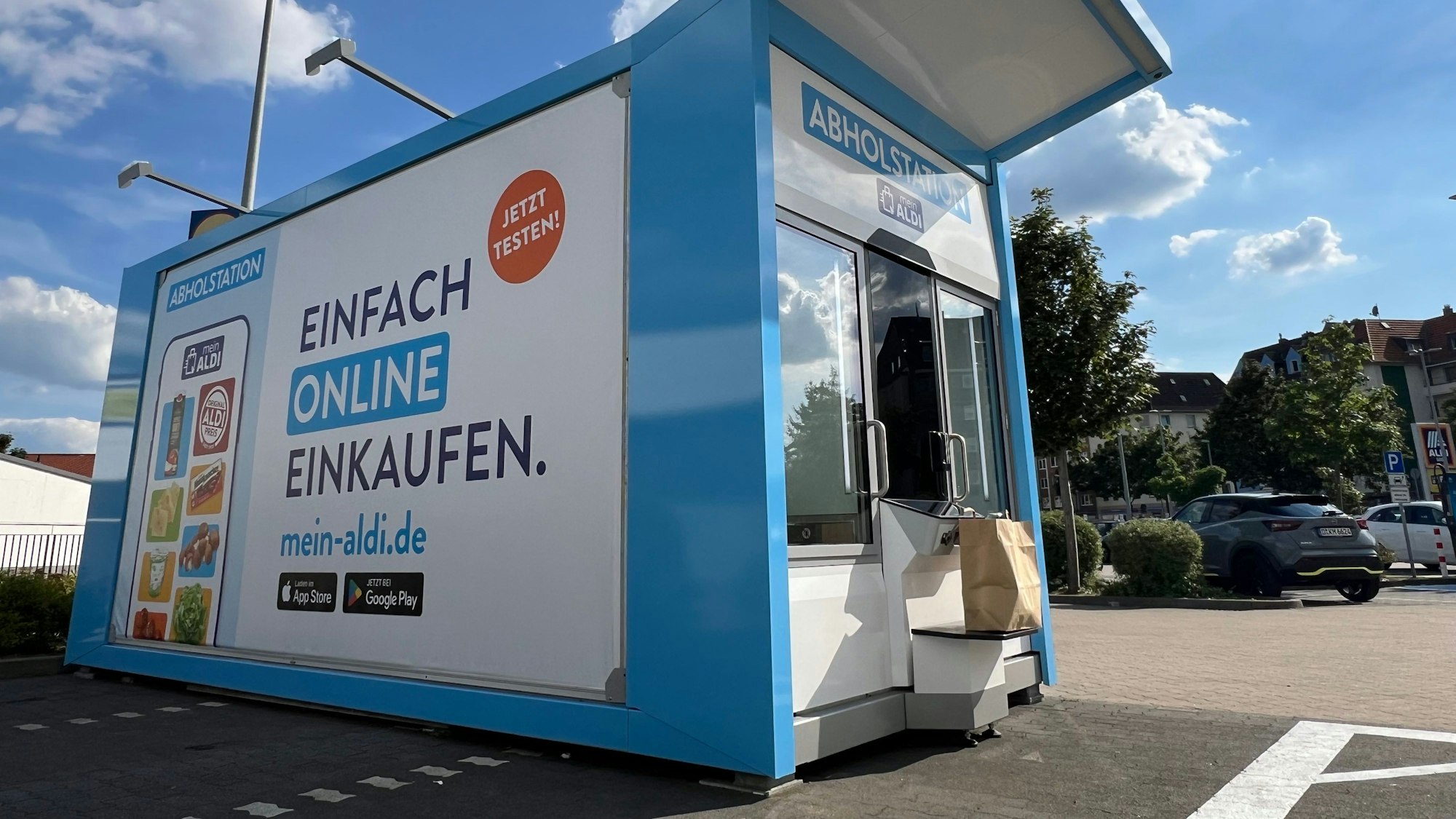 Ein Abholautomat, bei dem die Nutzer vorher online bei Aldi Süd Lebensmittel bestellt haben, steht an einem Parkplatz vor einer Filiale des Discounters.