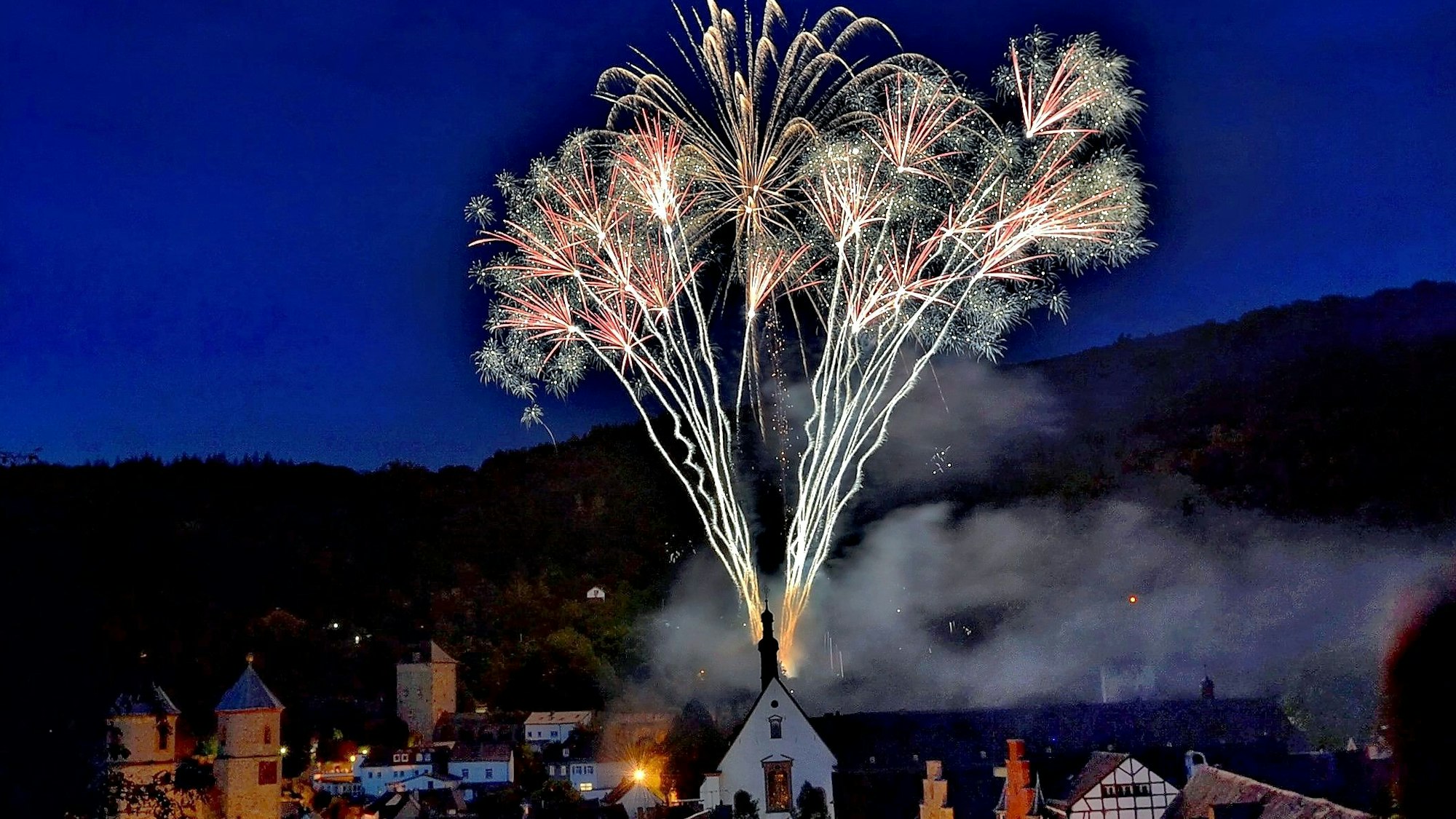 Ein Feuerwerk macht die Silhouette der Stadt Bad Münstereifel trotz Dunkelheit sichtbar.