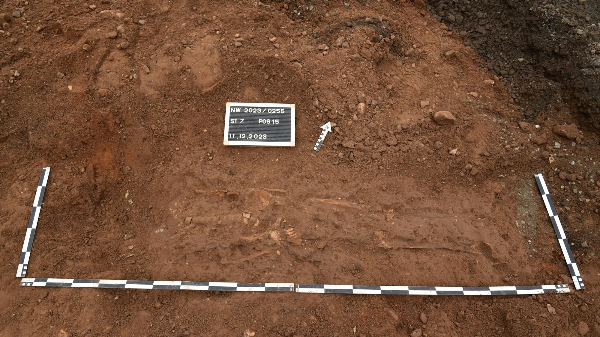 Das Foto zeigt die Grabstelle, Metermaße und eine Beschriftung zeigen die Größe der Fundstelle an.