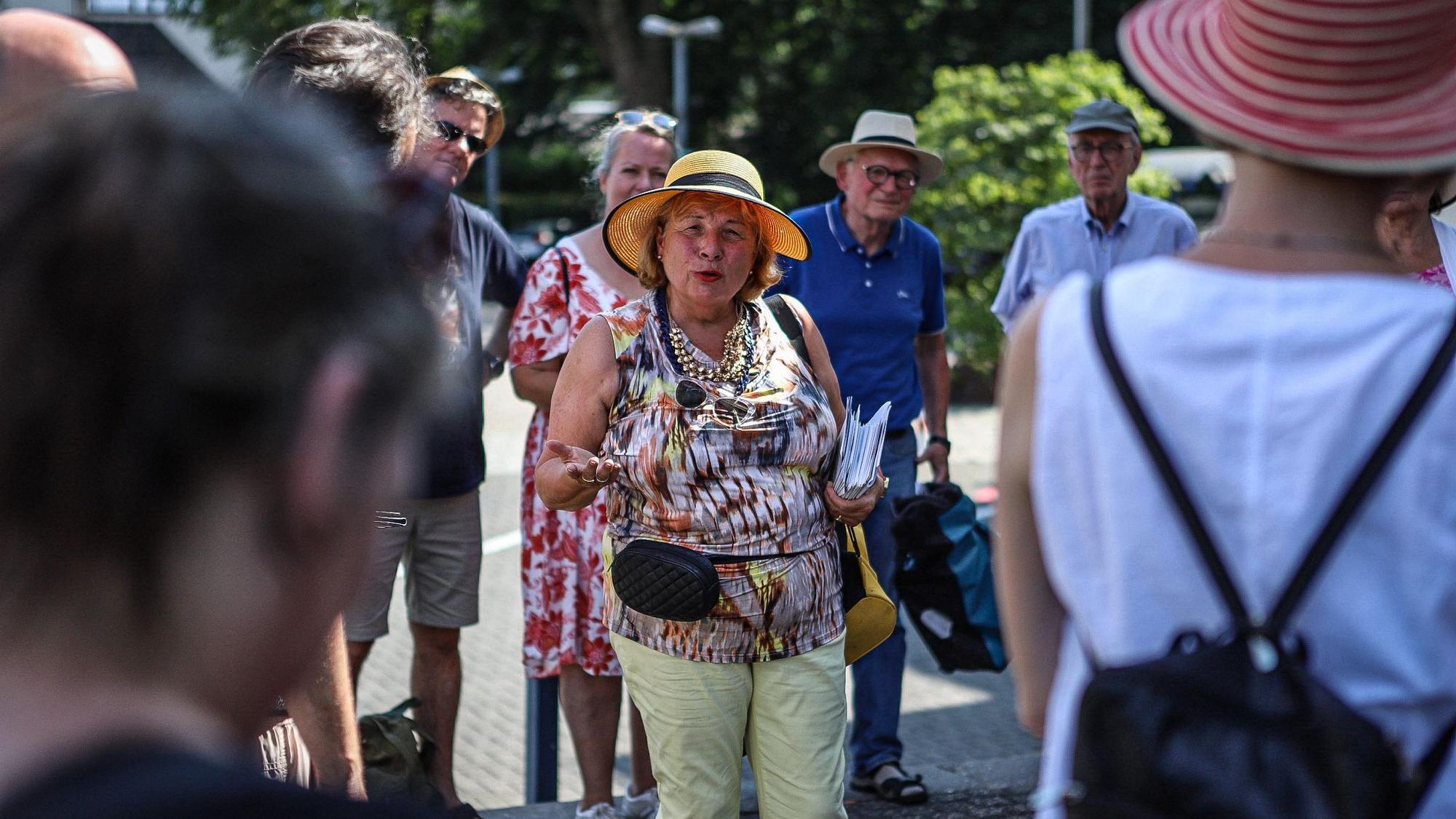 Eine Frau spricht umringt von einer Gruppe Menschen auf der Straße.