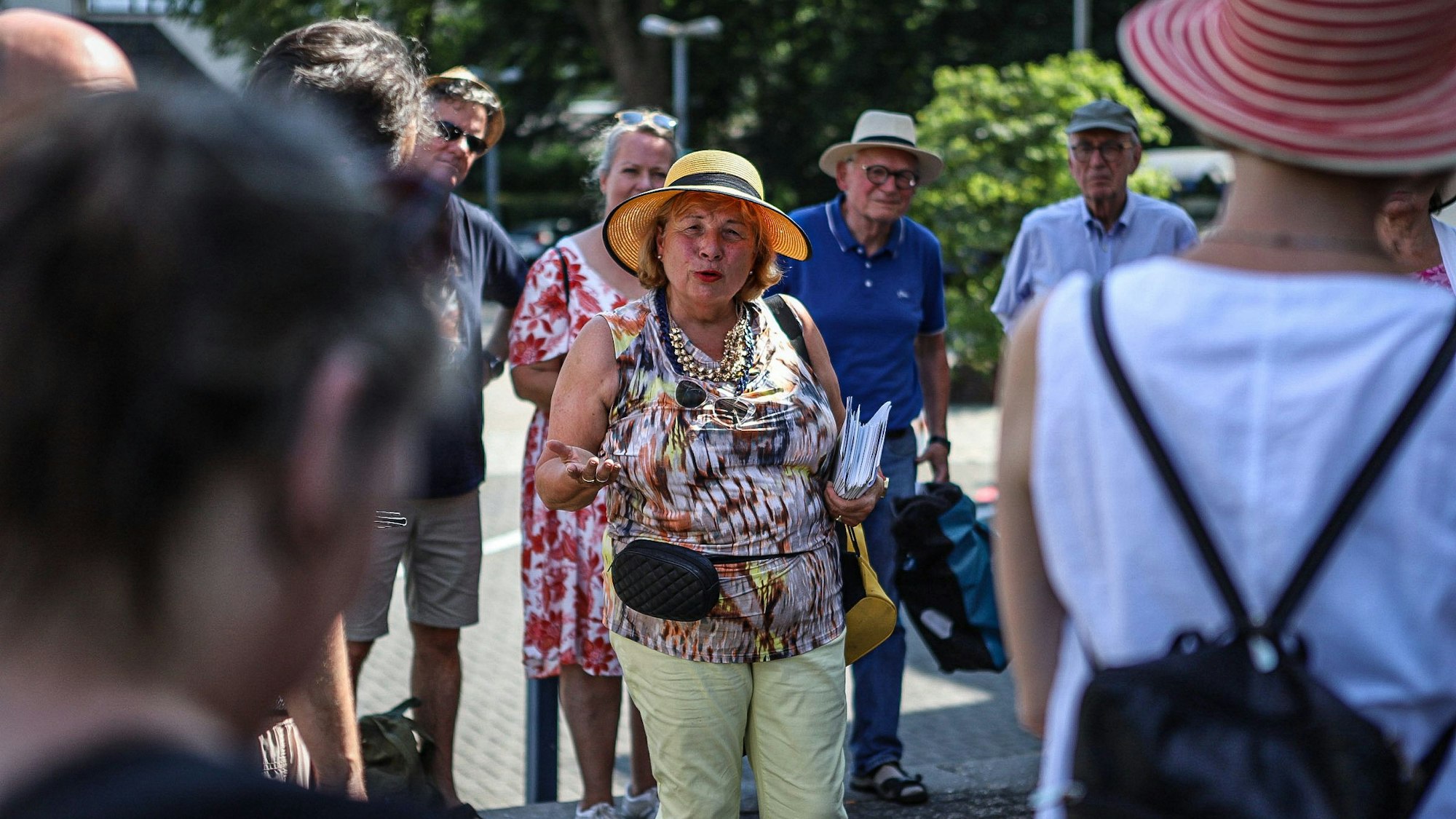 Eine Frau spricht umringt von einer Gruppe Menschen auf der Straße.