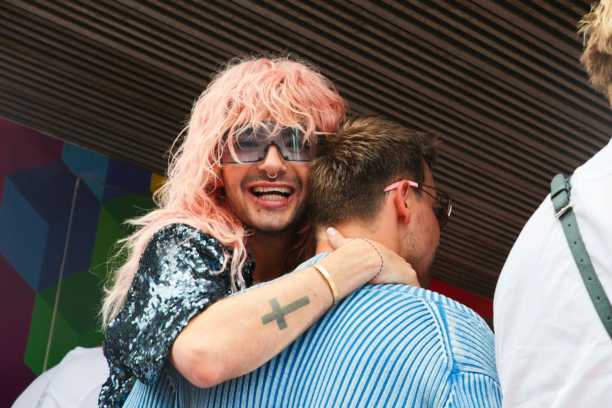 Bill Kaulitz lacht in die Kamera und umarmt einen Mann.