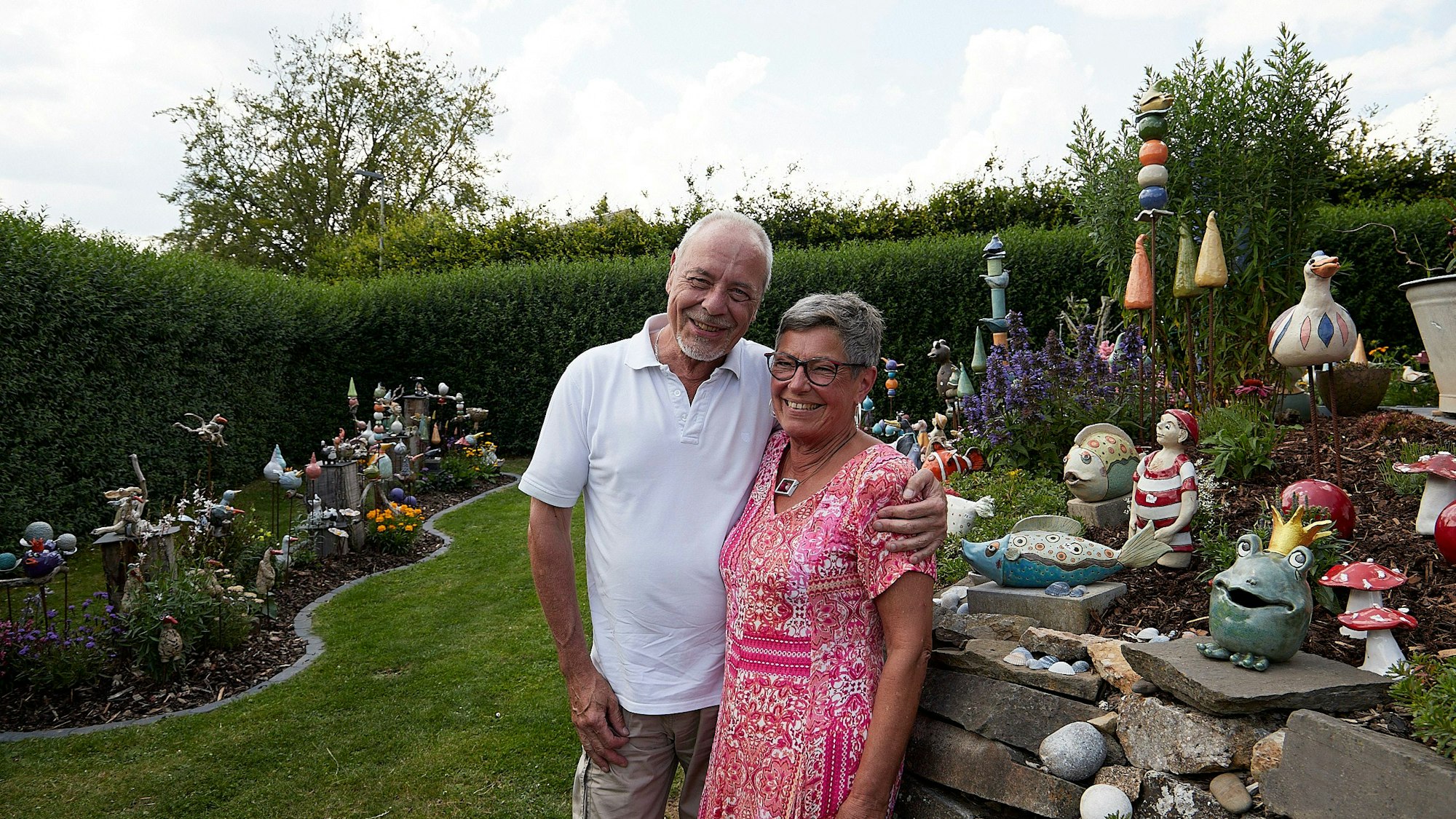Klara und Rainer Martens stehen in ihrem Garten. Er hält den Arm um sie, beide lächeln.
