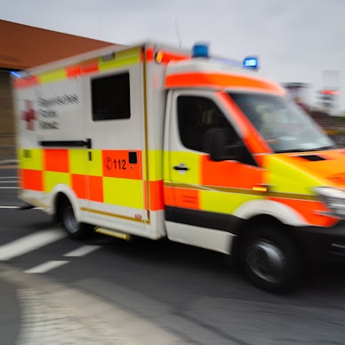 Es ist ein Krankenwagen zu sehen, der auf der Straße fährt.