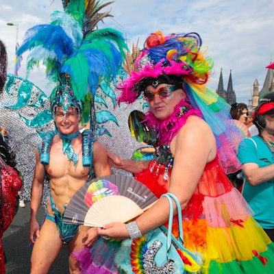 Männer in bunten Kostümen und Glitzer posieren beim CSD in Köln.