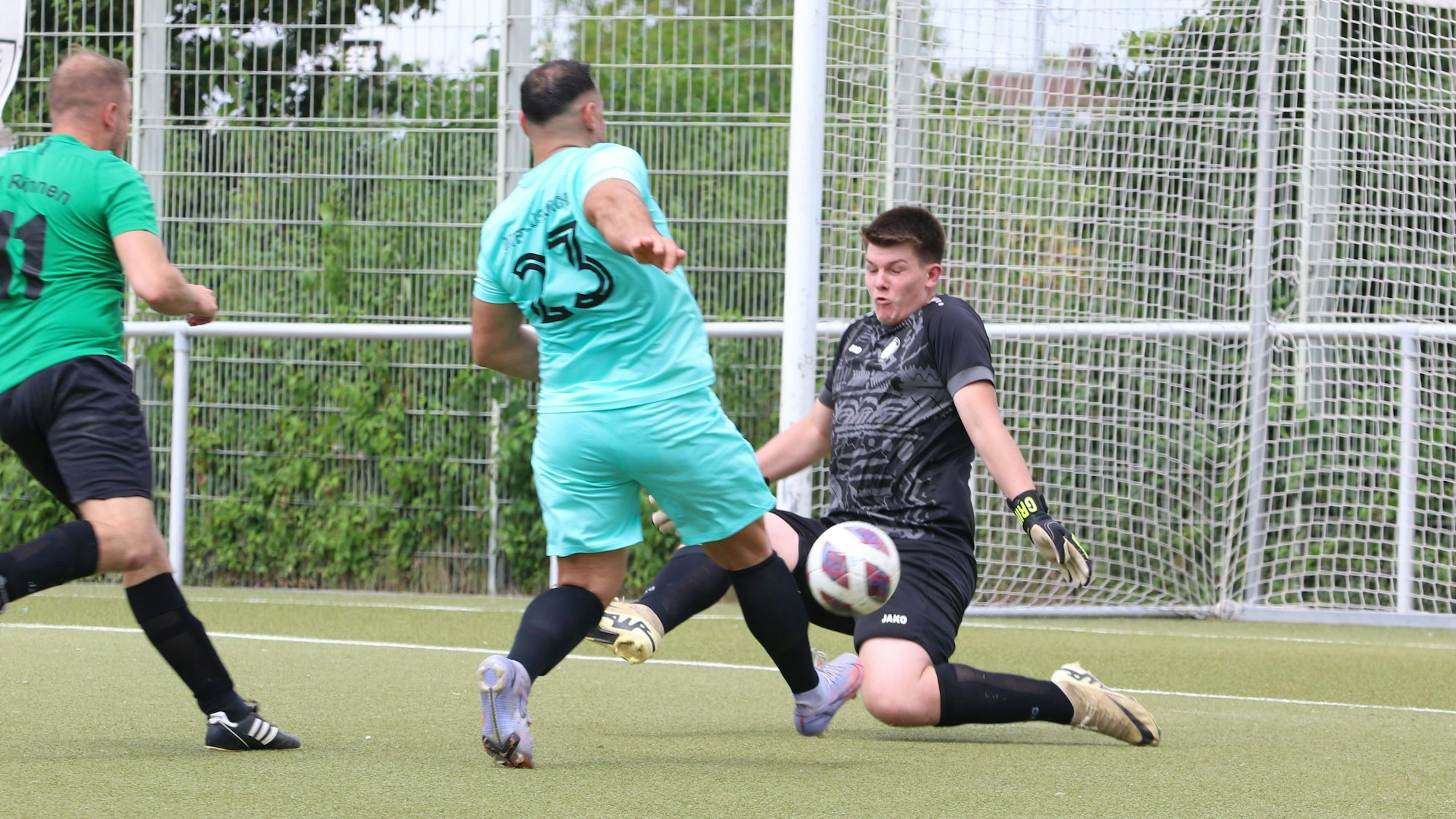 Ein Torwart wirft sich einem Stürmer entgegen und hält mit geschlossenen Augen dessen Schuss.