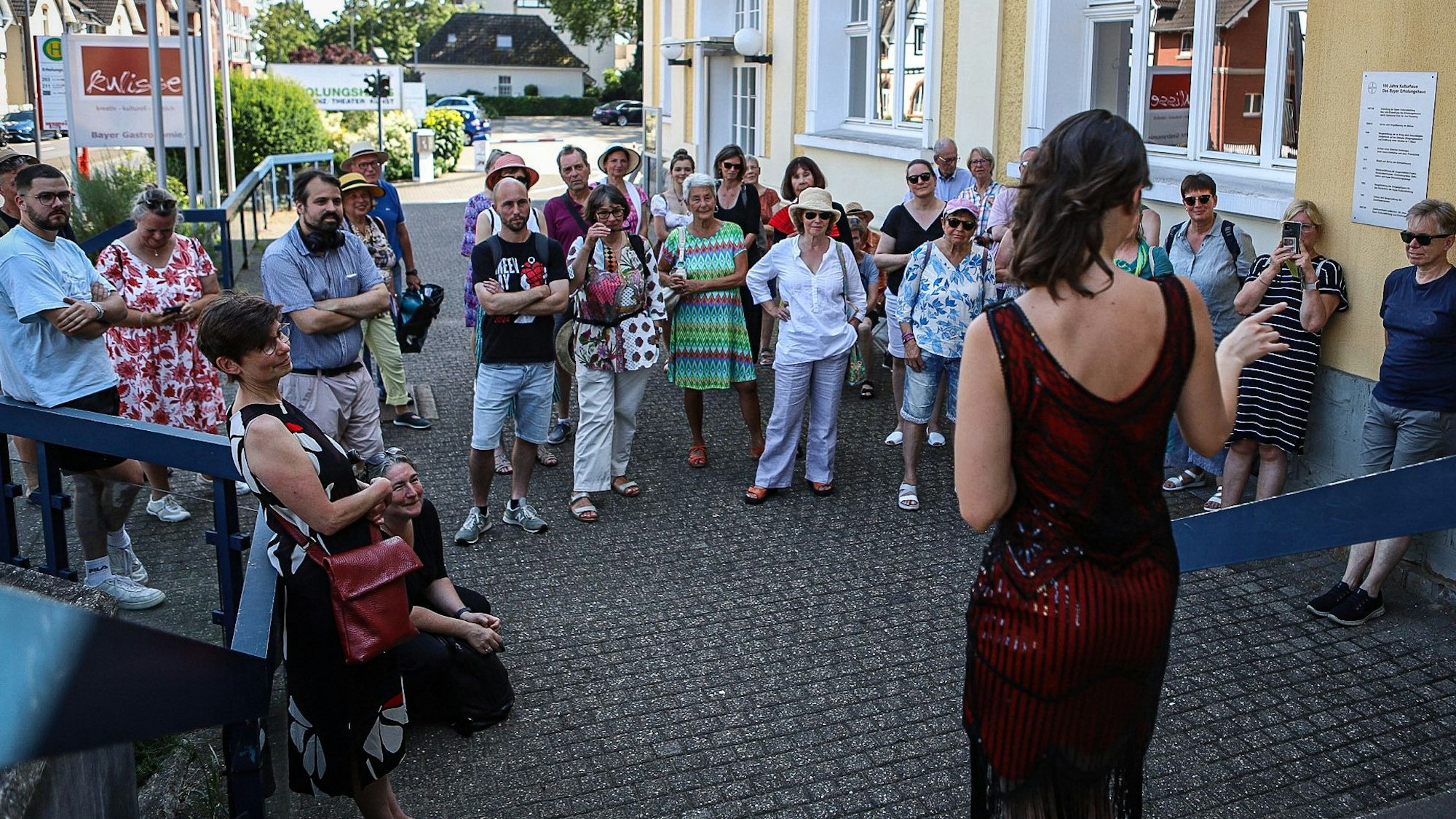 Eine junge Frau steht vor einer Menschengruppe am Erholungshaus