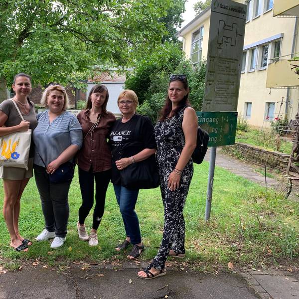 Fünf Frauen stehen vor einem Haus.