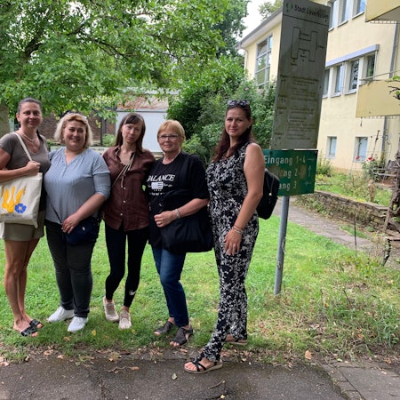 Fünf Frauen stehen vor einem Haus.