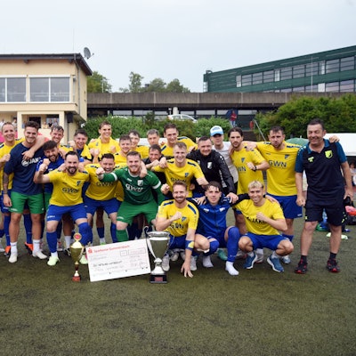 Die Landesliga-Fußballer des SSV Nümbrecht jubeln mit  den Pokalen und dem Siegerscheck in die Karmera.