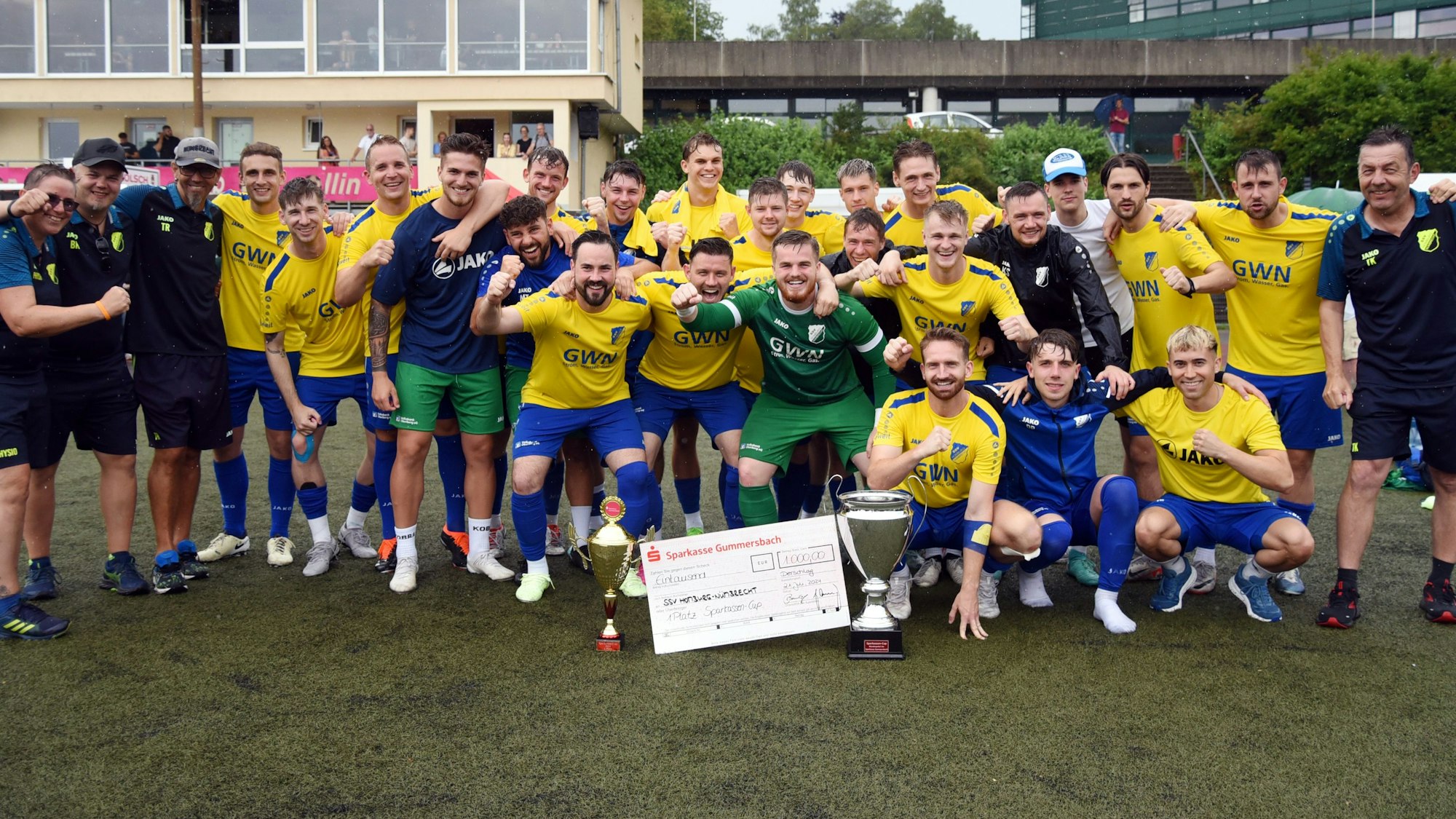 Die Landesliga-Fußballer des SSV Nümbrecht jubeln mit  den Pokalen und dem Siegerscheck in die Karmera.