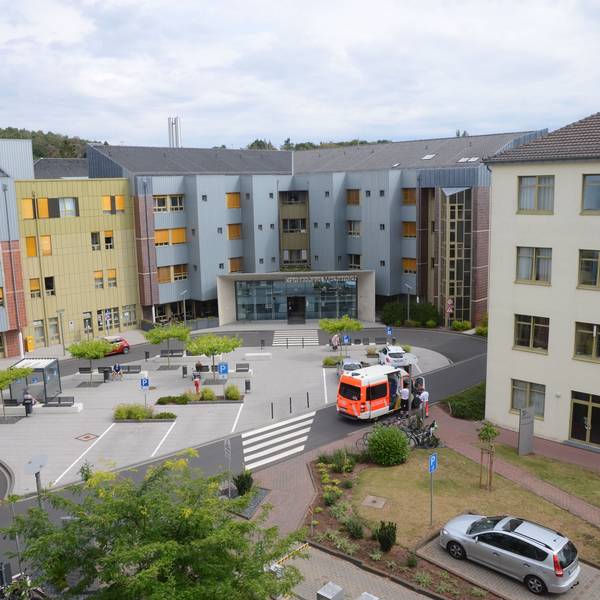 Außenansicht des Haupteingangs des Kreiskrankenhauses Mechernich. Ein Rettungswagen hält nahe der Einfahrt. Das Foto wurde aus erhöhter Perspektive aufgenommen.