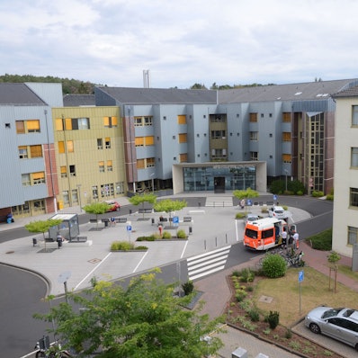 Außenansicht des Haupteingangs des Kreiskrankenhauses Mechernich. Ein Rettungswagen hält nahe der Einfahrt. Das Foto wurde aus erhöhter Perspektive aufgenommen.