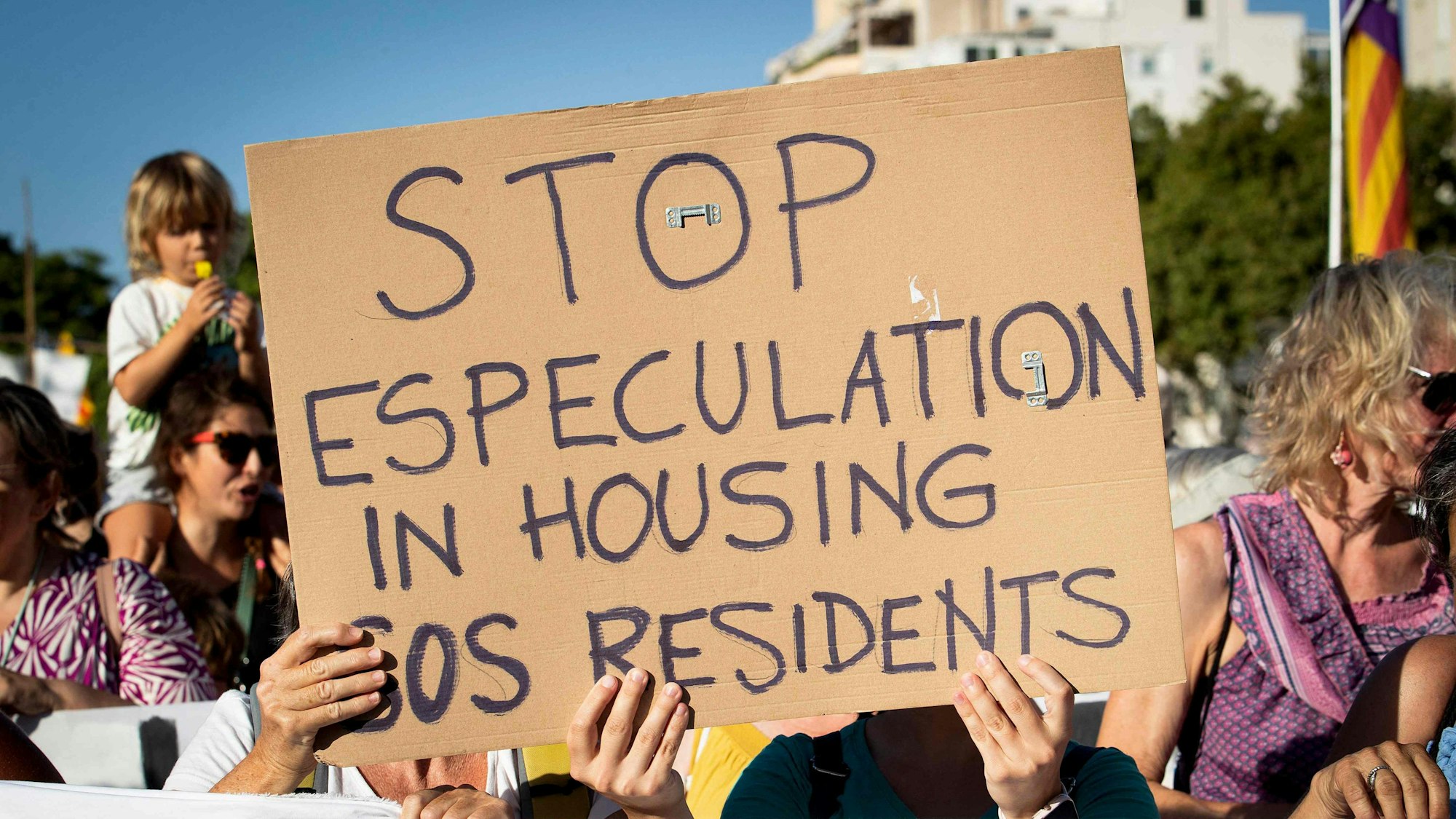 Menschen halten ein Plakat, als sie am 21. Juli 2024 in Palma de Mallorca an einer Demonstration gegen den Übertourismus und die Immobilienpreise auf der Insel Mallorca teilnehmen.
