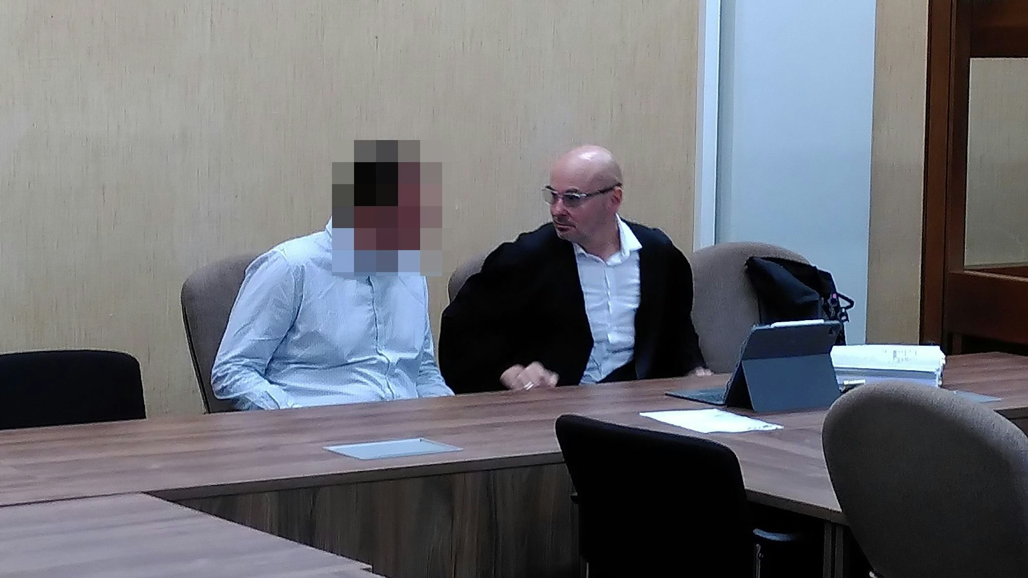 Auf dem Bild ist der Angeklagte mit verpixeltem Gesicht neben seinem Verteidiger im Gerichtssaal zu sehen.