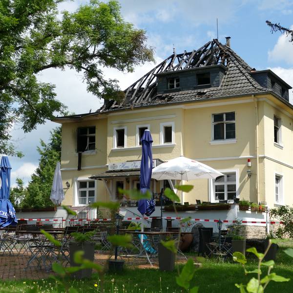 Ein Feuerwehrmann in einem Drehleiterkorb vor einem brennenden Dachstuhl.