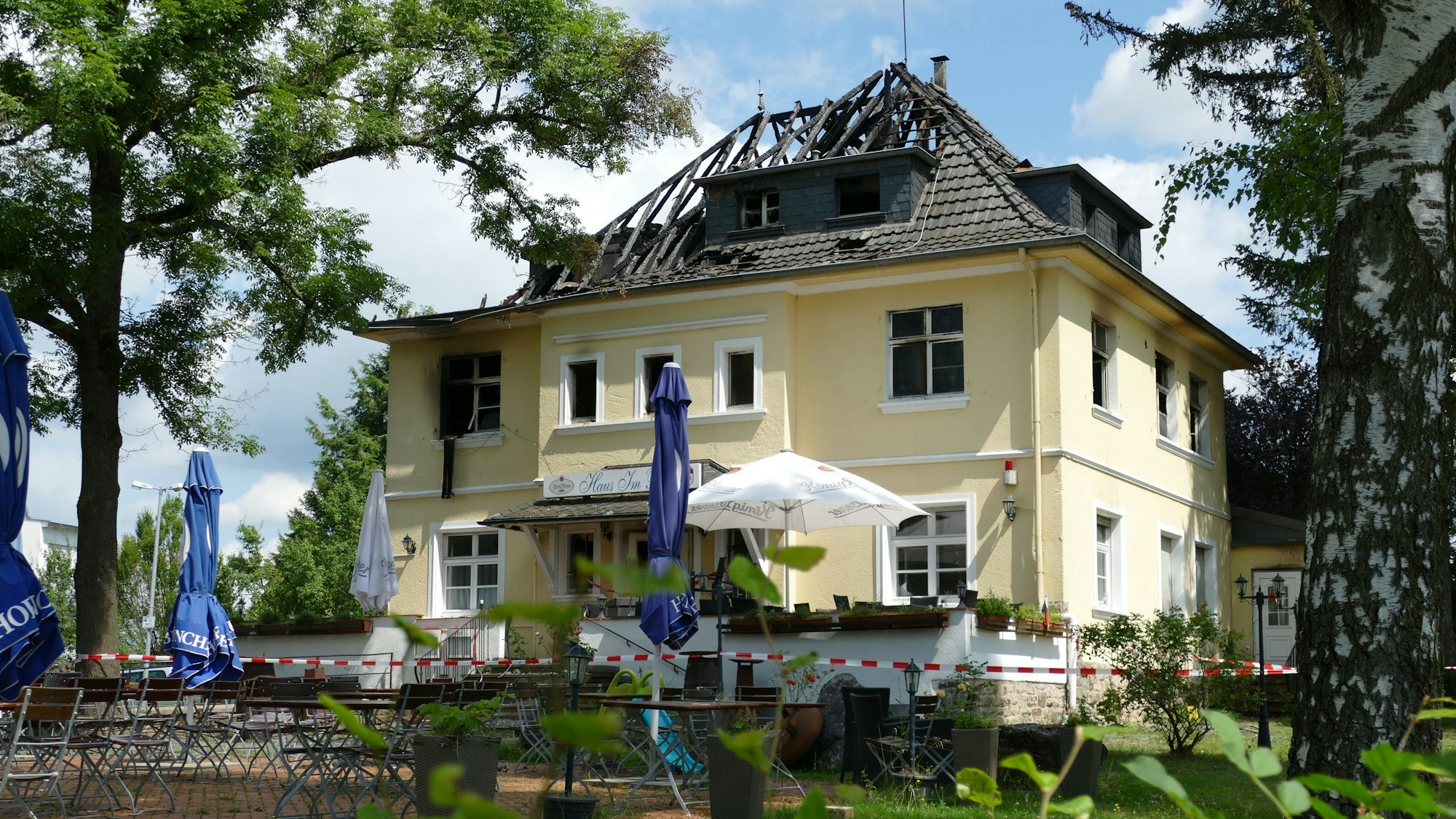 Ein Feuerwehrmann in einem Drehleiterkorb vor einem brennenden Dachstuhl.