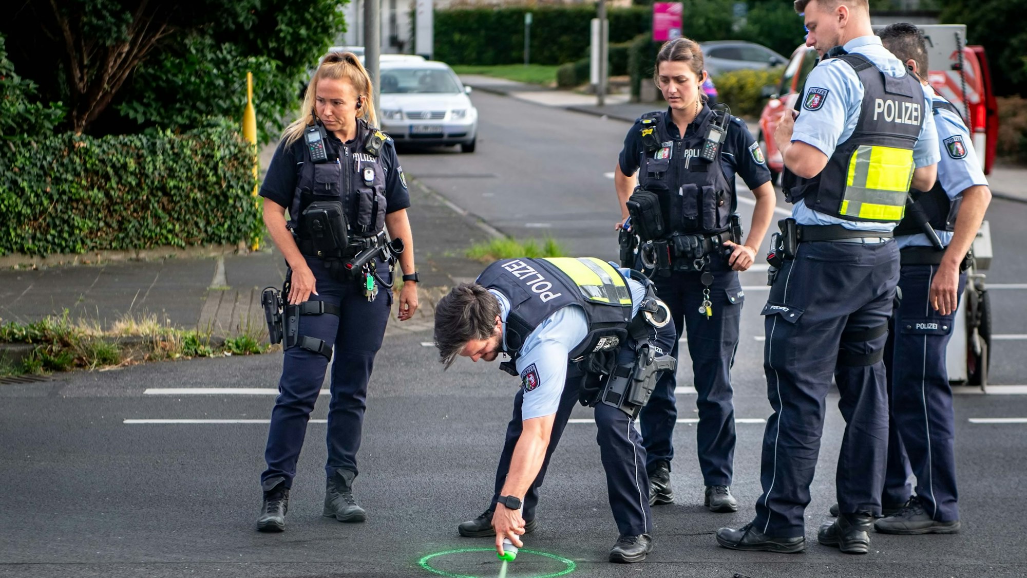 Das Bild zeigt Polizeibeamte an einer Unfallstelle, die Spuren sichern.