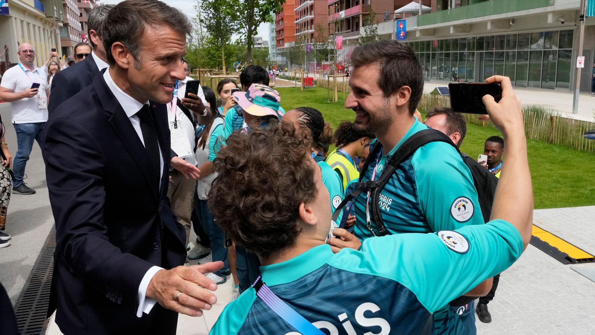 Frankreichs Präsident Emmanuel Macron posiert mit Volunteers für ein Foto.