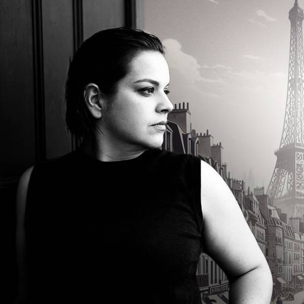 Auf dem Bild ist Rosa Halina Dahm zu sehen, sie schaut verträumt zur Seite. Im Hintergrund ein historisches Bild der Stadt Paris und der Eifelturm im Hintergrund. Das Bild ist schwarz-weiß.