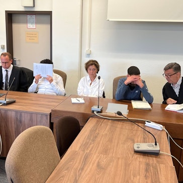 Die Angeklagten mit ihren Verteidigern und einer Dolmetscherin beim Prozessauftakt im Landgericht Köln