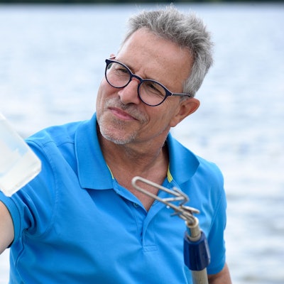 Ein Mann an einem See hält eine Flasche in der Hand.