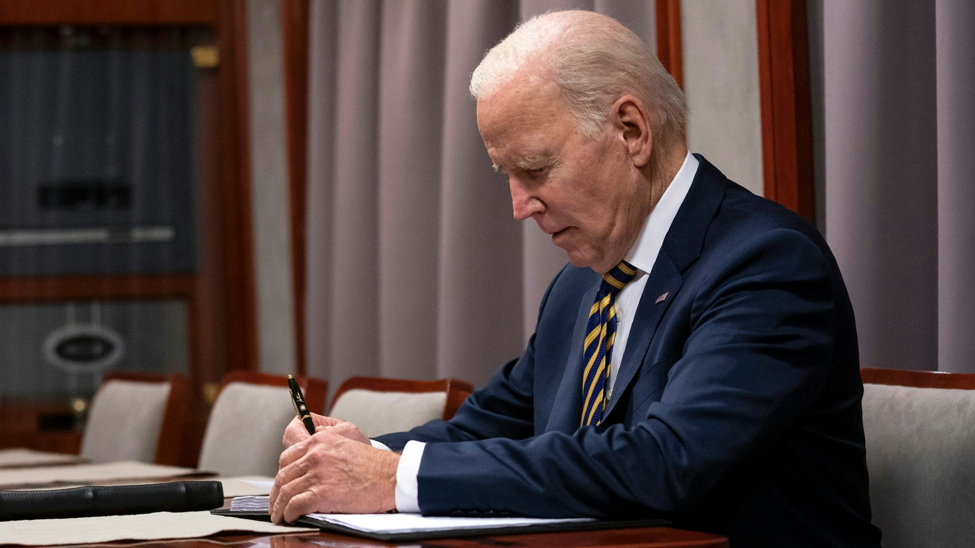 US-Präsident Joe Biden sitzt im Oval Office über einem Gesetzesentwurf und unterschreibt diesen.