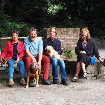 Hundehalter und ihre Hunde sitzen auf einer Bank im Park.