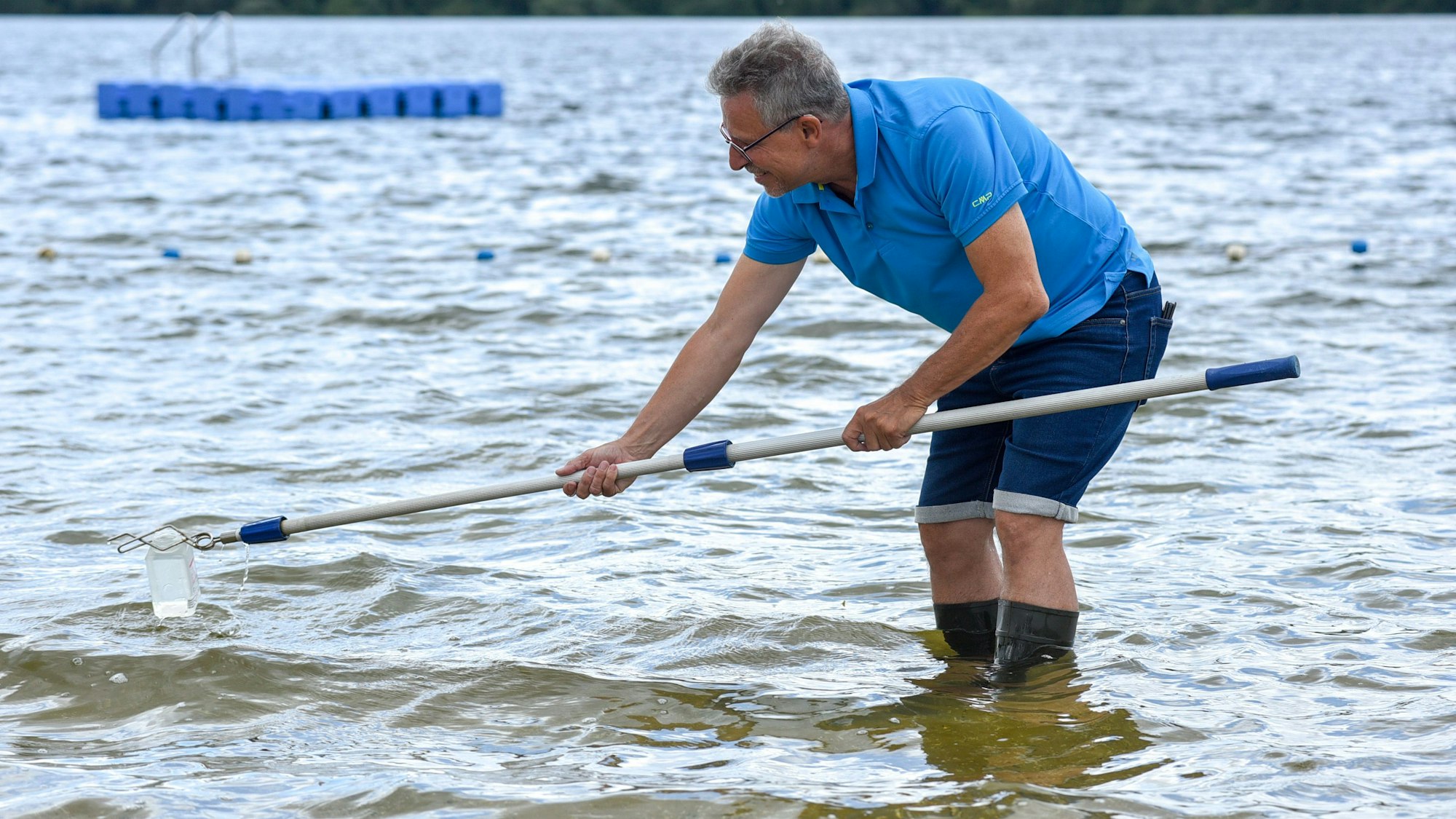 Ein Mann nimmt eine Gewässerprobe aus einem See.