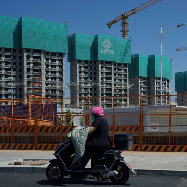 Eine Frau fährt an einem im Bau befindlichen Wohnprojekt am Stadtrand von Peking vorbei.