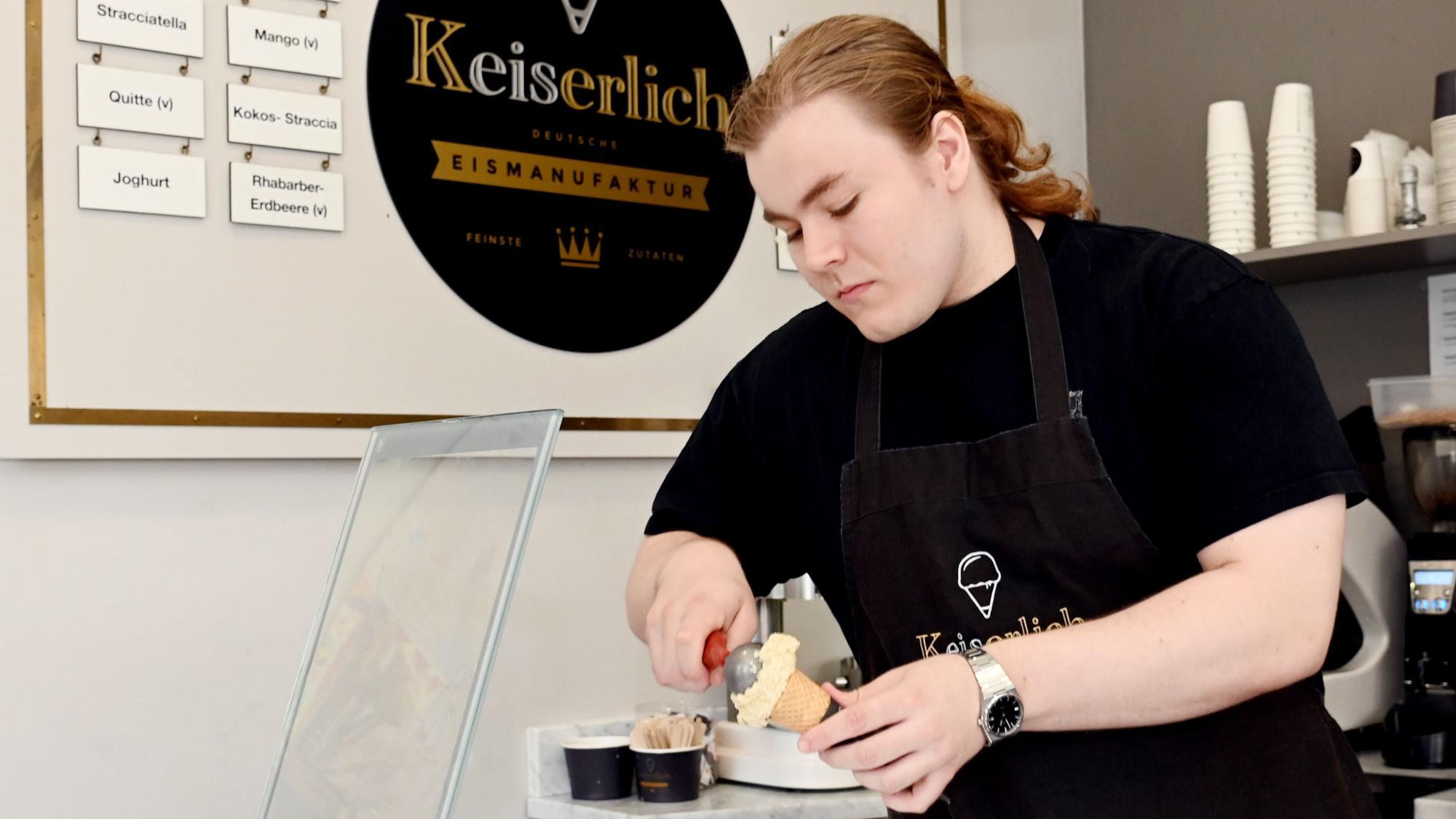 Eisverkäufer Loïk portioniert eine Kugel Eis