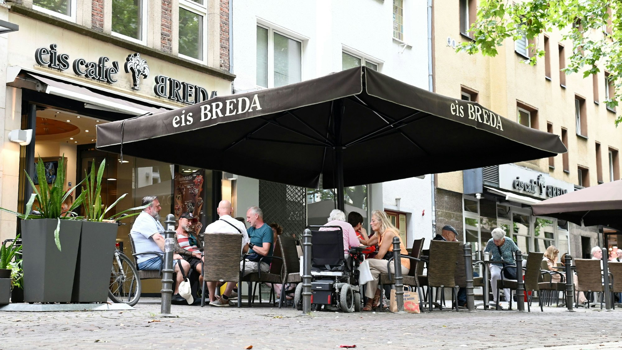 Gäste sitzen auf der Terrasse vor dem Eiscafé Breda auf der Pfeilstraße