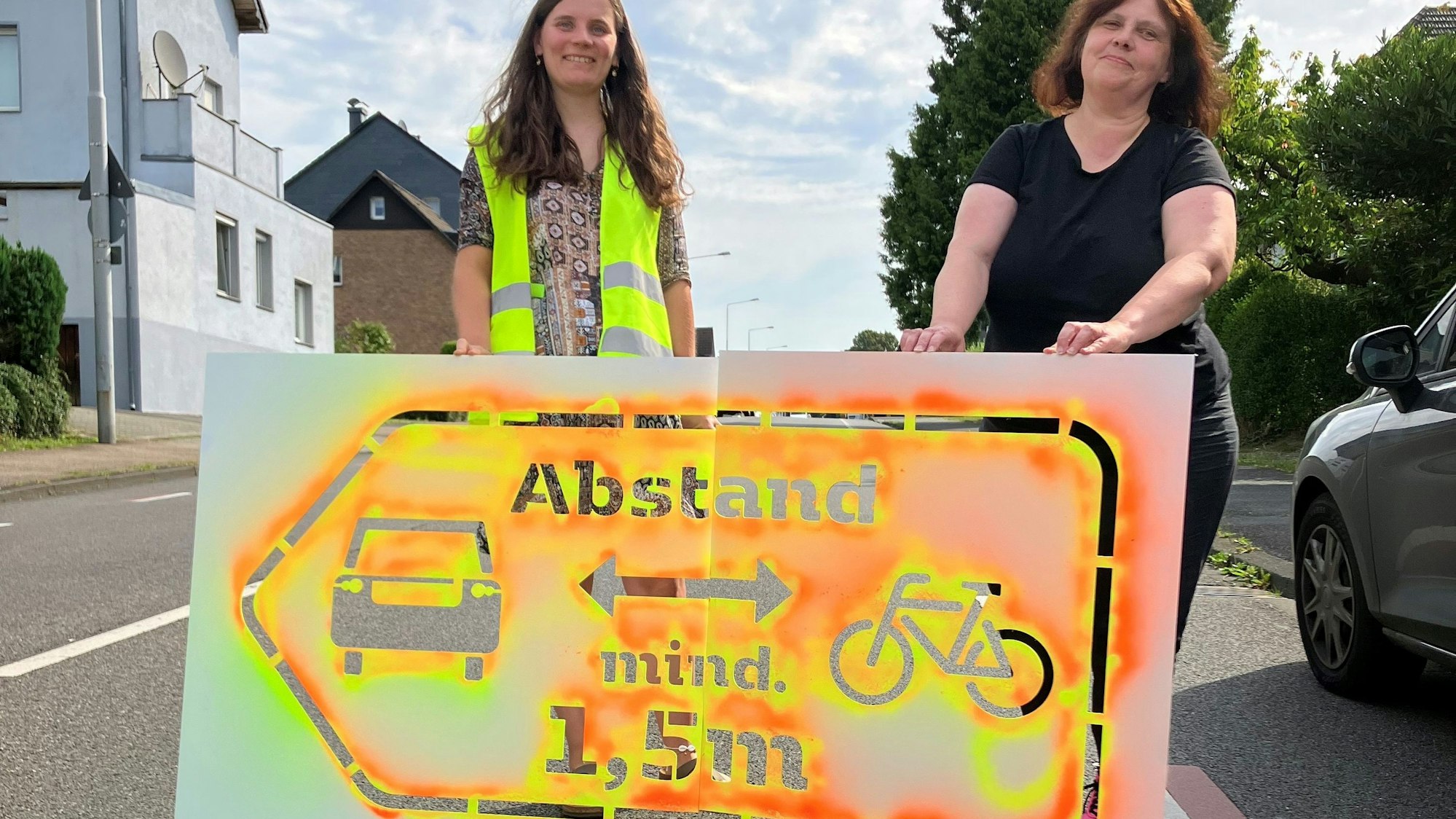 Zwei Frauen stehen hinter einem Sprühsymbol auf der Straße.