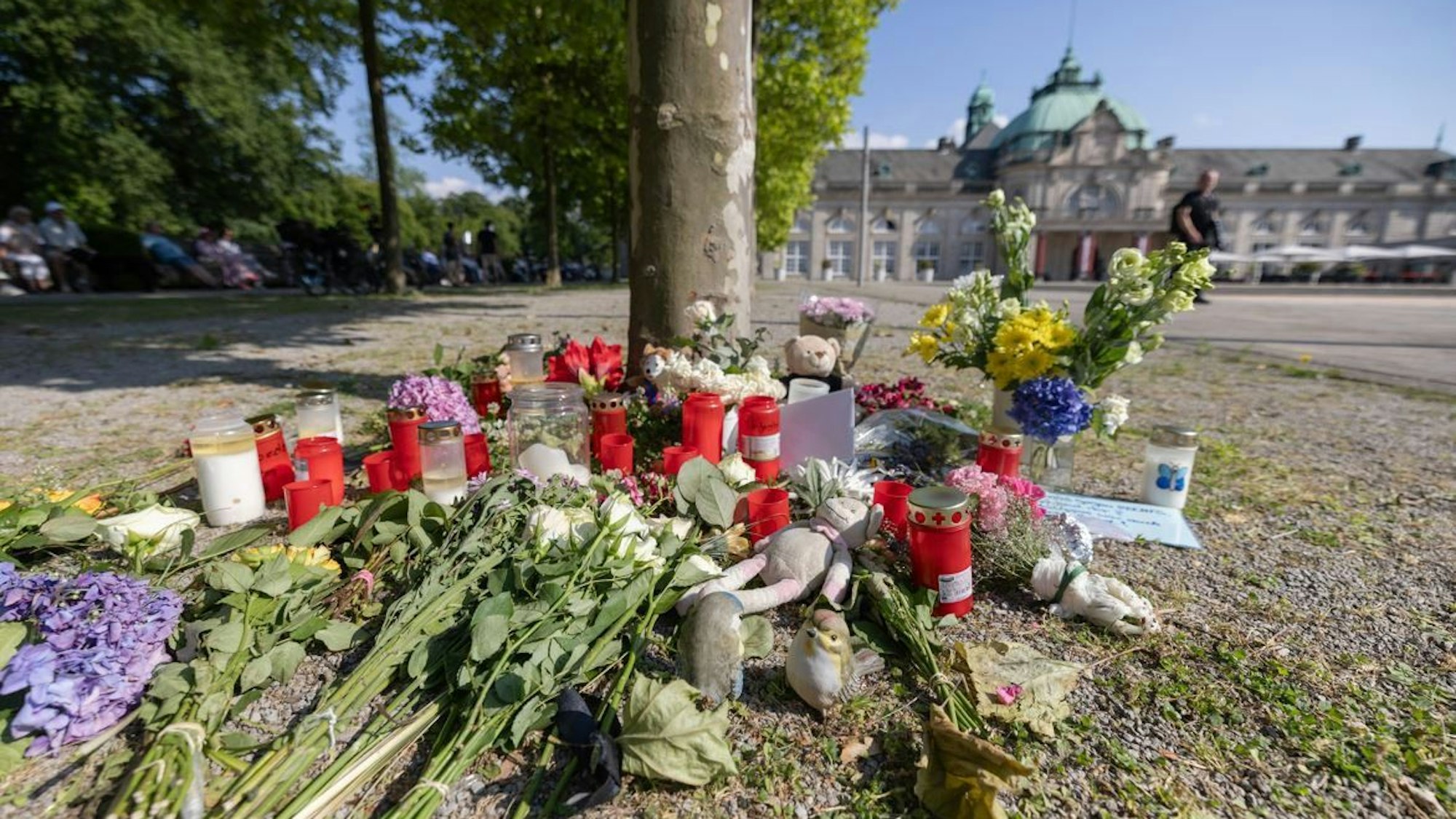 Blumen, Kerzen und handgeschriebene Trauerbekundungen stehen an einem Baum im Kurpark Bad Oeynhausen. Nach der tödlichen Attacke im Kurpark hatte die Polizei einen 18-jährigen Tatverdächtigen festgenommen.