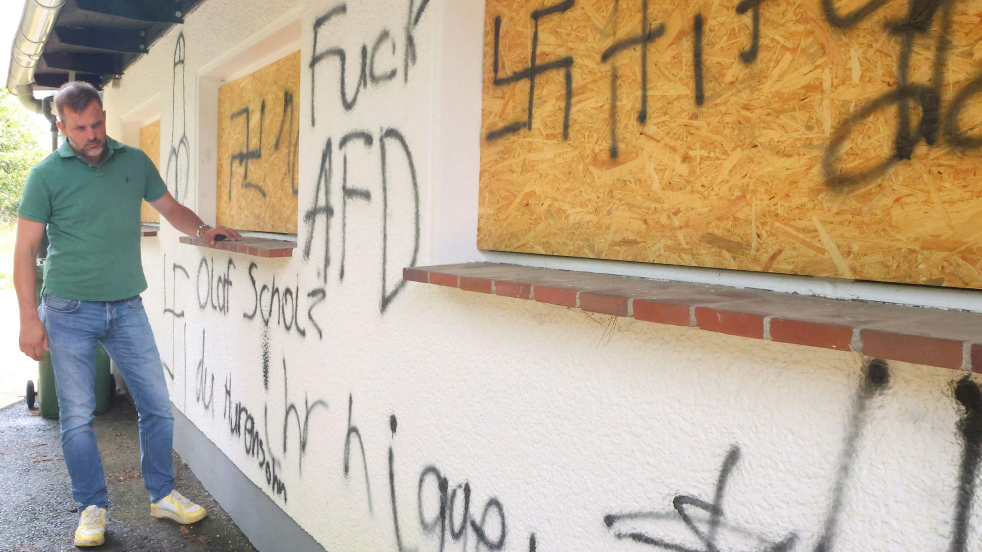 Der Waldbröler Unternehmer Michael Kappenstein steht an der beschmierten Wand seines Firmengebäudes an der Talstraße. Inzwischen gibt es offenbar ein Foto, das die Täter bei der Flucht zeigen könnte.