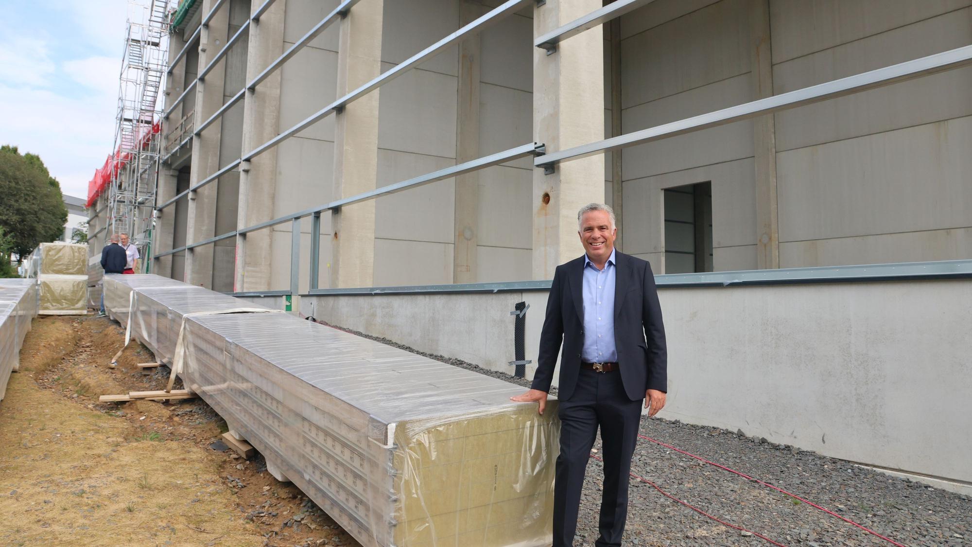 Ein Firmenchef vor einer sich im Bau befindenden neuen Halle.