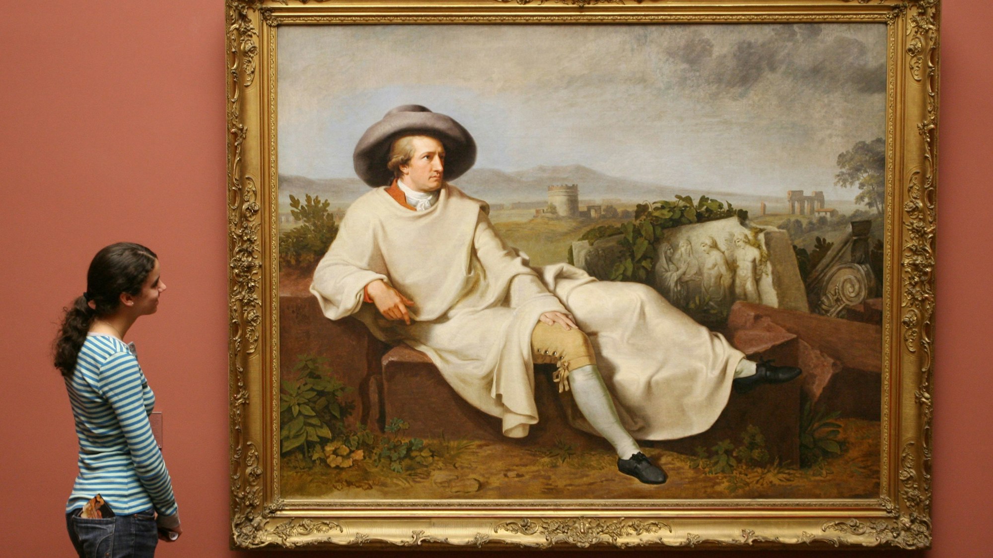 Eine Frau steht vor einem Bildnis von Goethe.