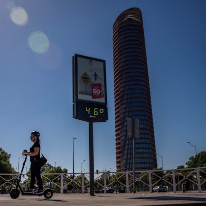 Eine Frau fährt auf einem E-Roller, im Hintergrund zeigt ein Thermometer 46 Grad an.