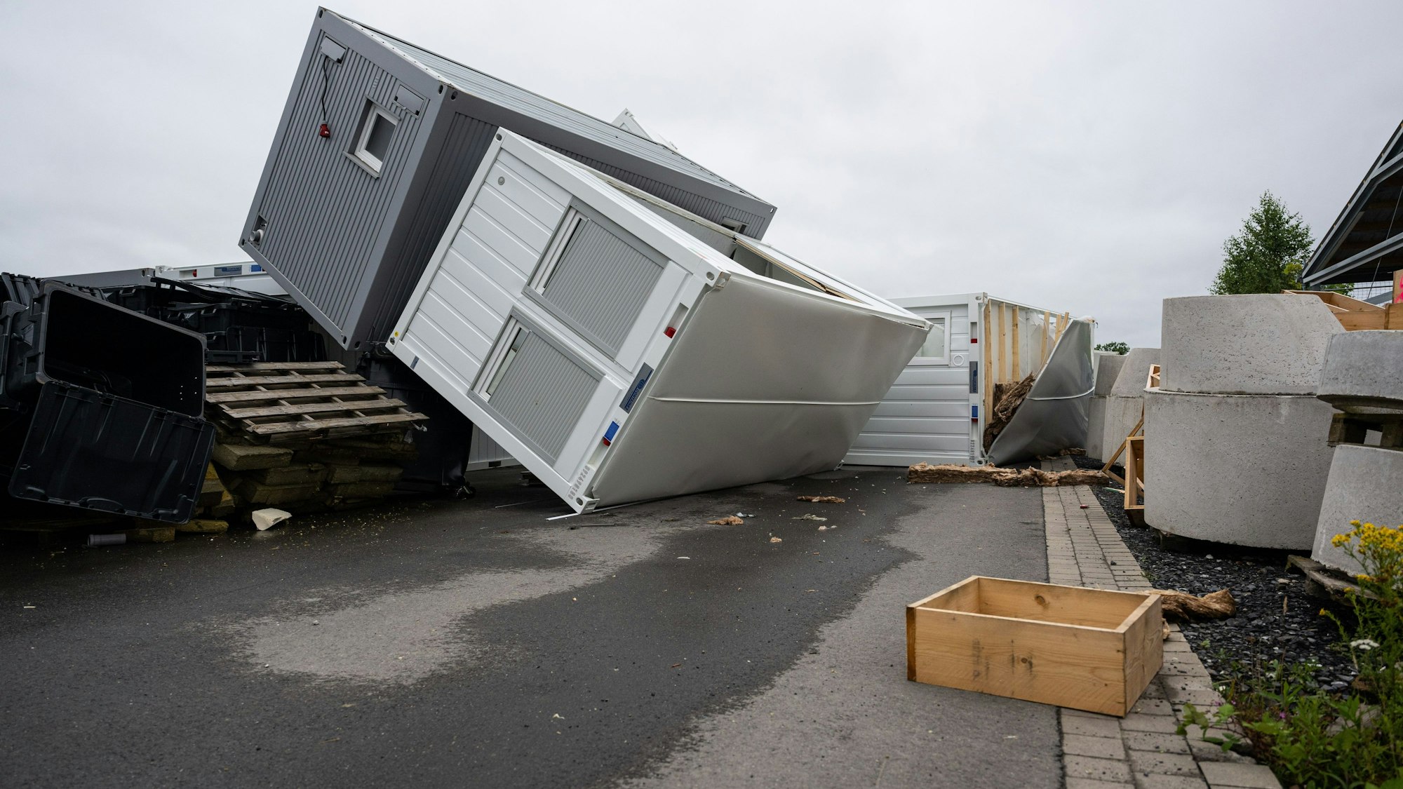 Umgestürzte Container, Bauteile und Trümmer liegen nach einem Sturm auf einem Hof einer Firma in Telgte.