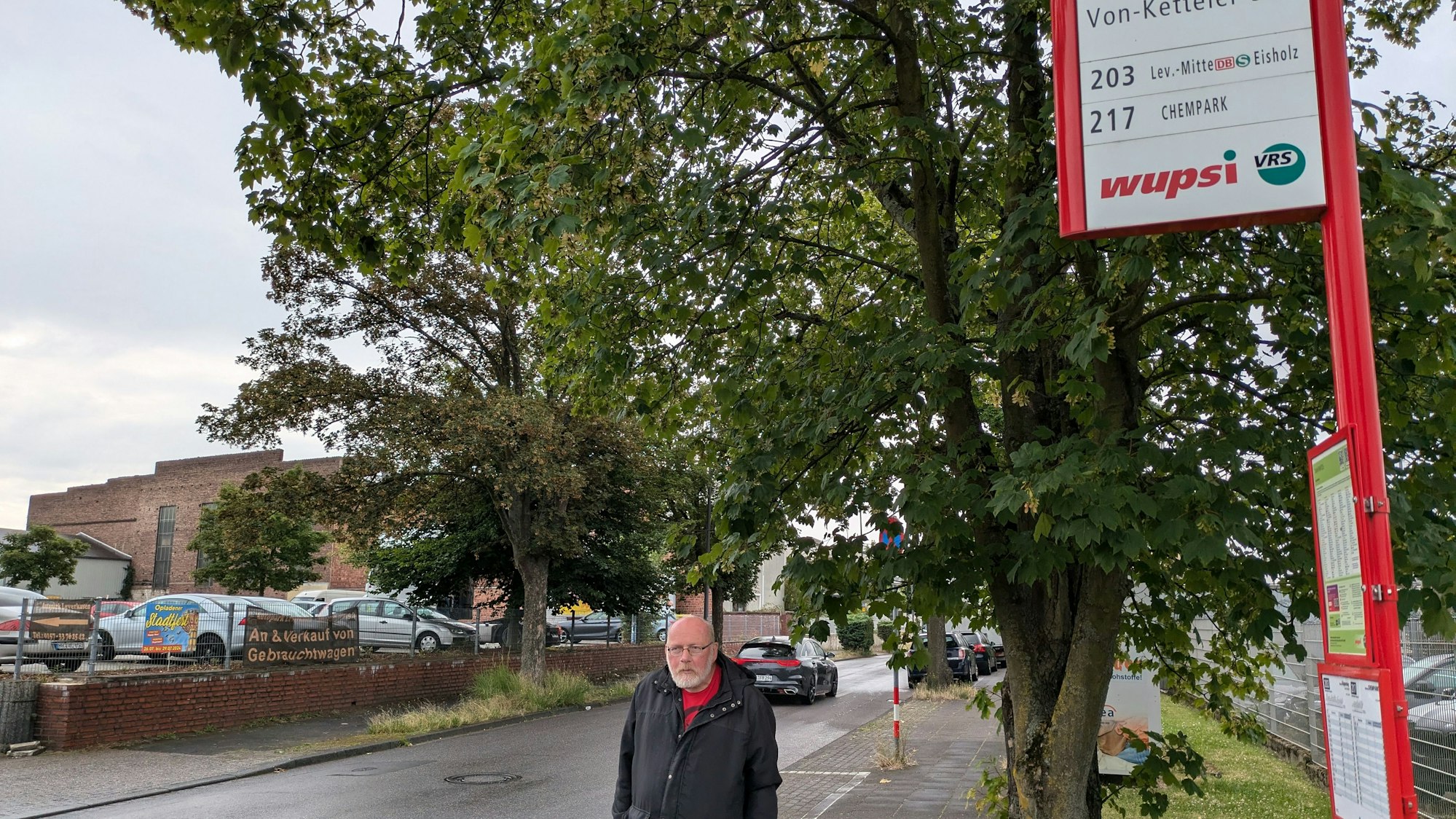 Ein Mann steht an einer Bushaltestelle.