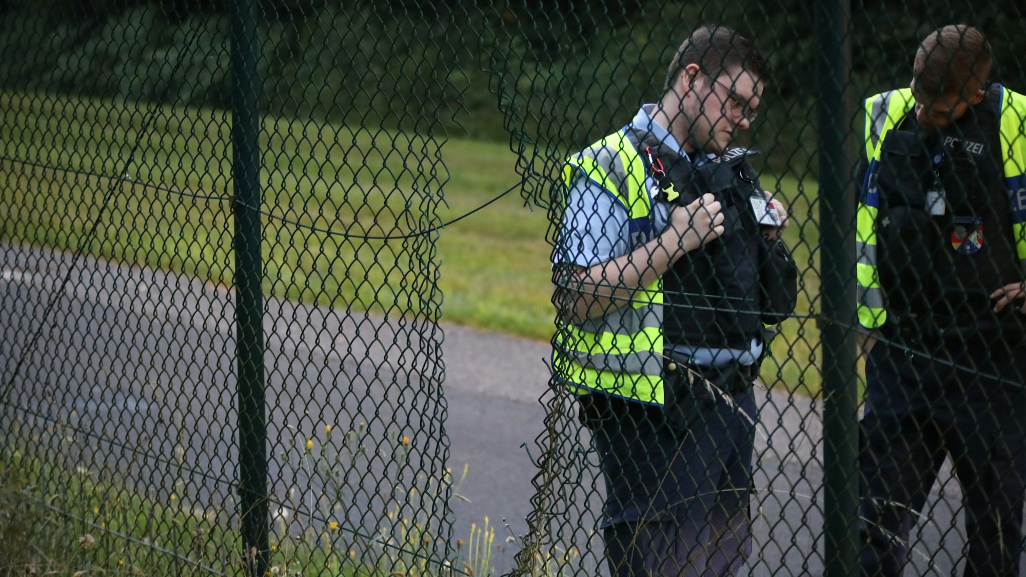 Einsatzkräfte der Polizei stehen neben einem Loch im Zaun am Flughafen Köln/Bonn. Klimaaktivisten haben am Flughafen Köln/Bonn eine Unterbrechung des Flugverkehrs verursacht.