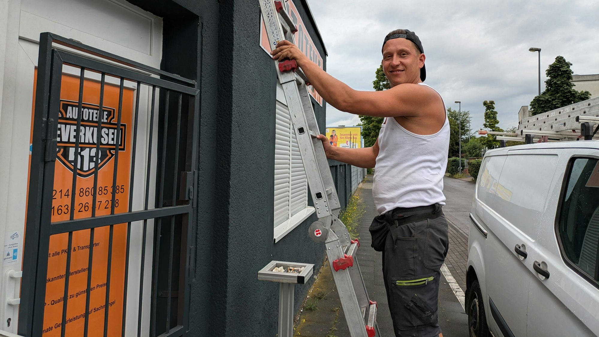 Ein Mann steht auf einer Leiter, die an ein Haus gelehnt ist.