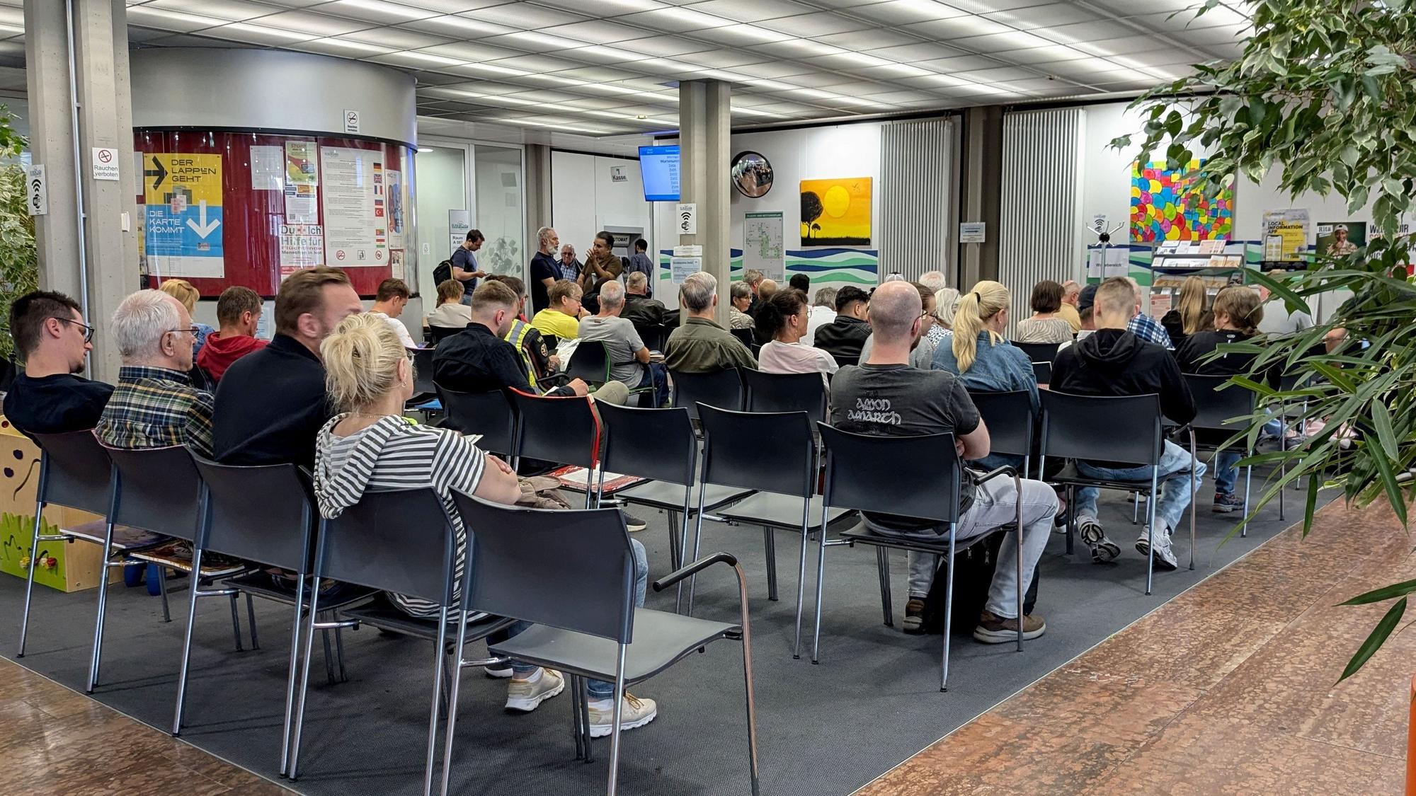 Zahlreiche Menschen sitzen auf grauen Stühlen vor der Zulassungsstelle im Kreishaus in Euskirchen und warten.